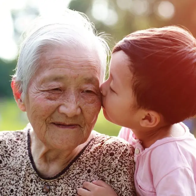 senior woman getting a kiss from a little boy on the cheek