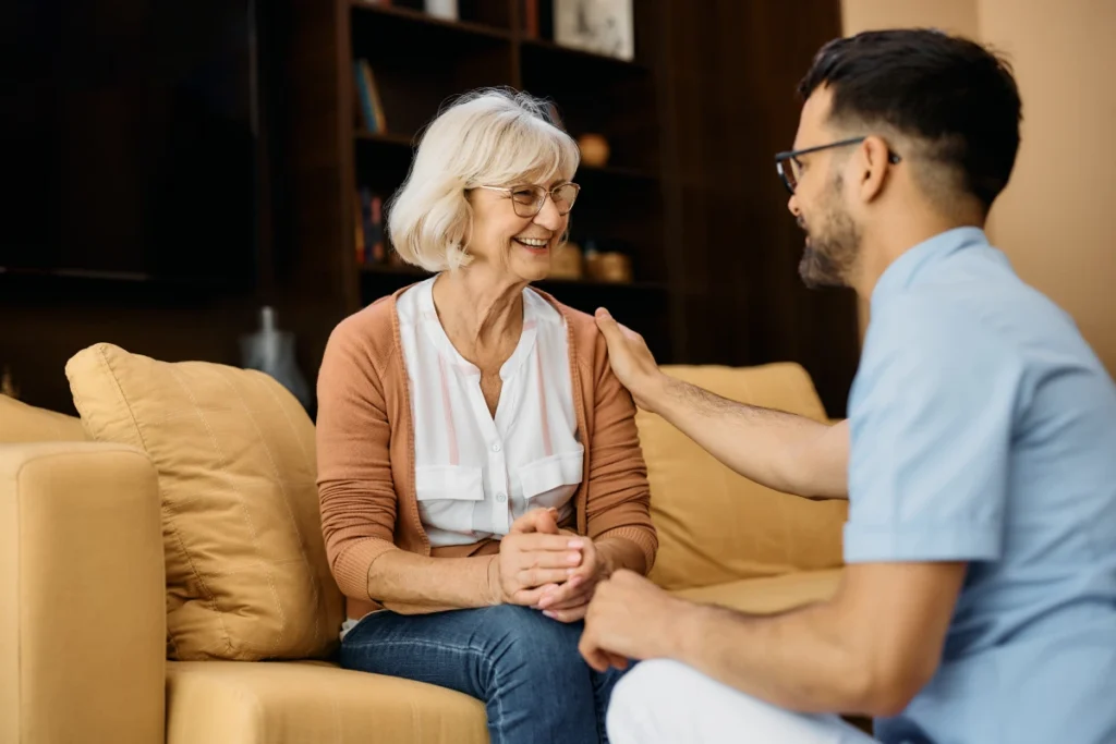 Caregiver comforting senior woman on couch
